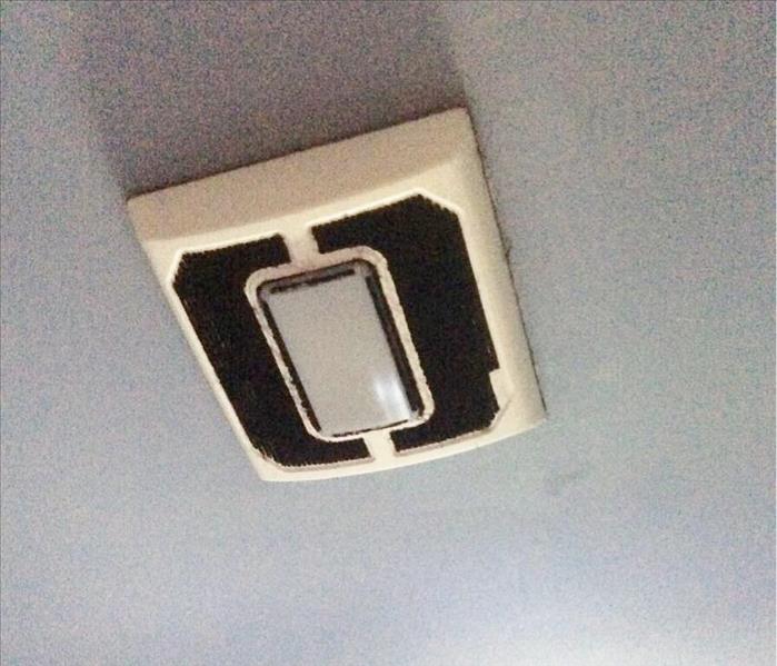 White ceiling exhaust fan with black soot in the vents