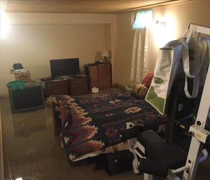 Water completely covering carpet surrounding a bed and other bedroom items