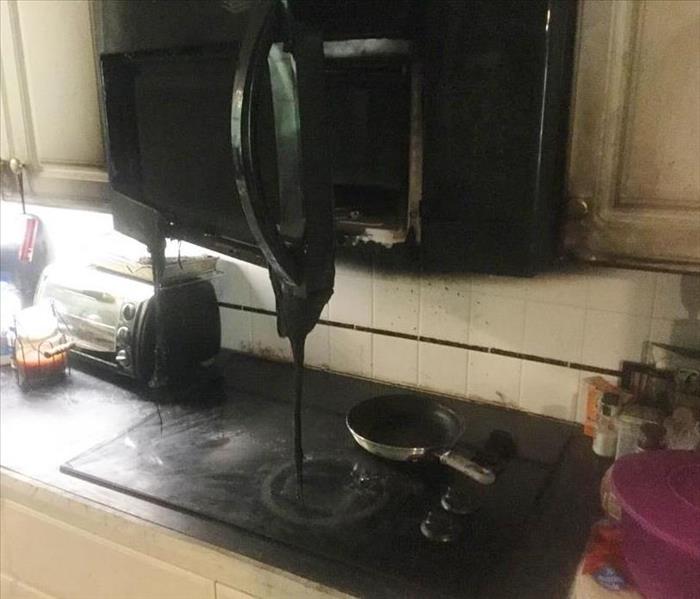 Melted microwave and charred cabinets over cooktop stove