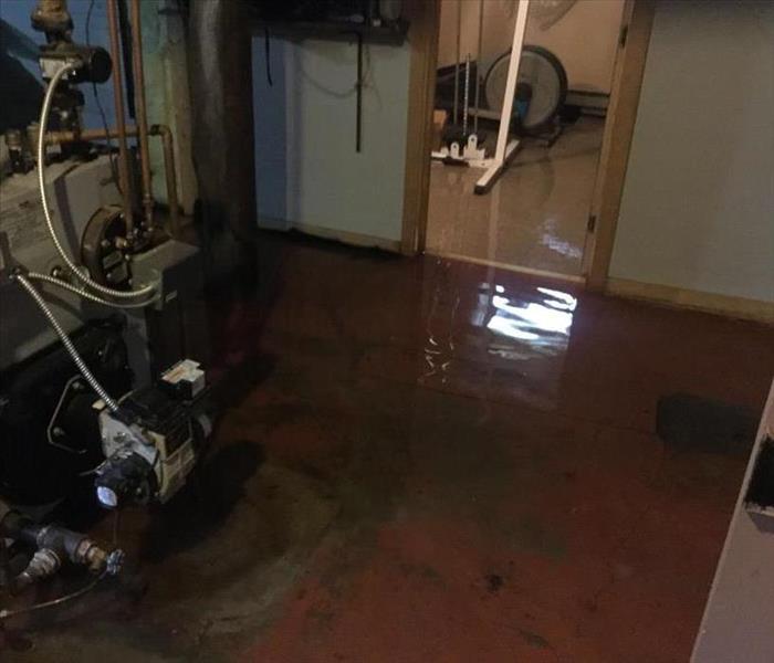 Furnace and exercise equipment in basement with inches of water on the floor