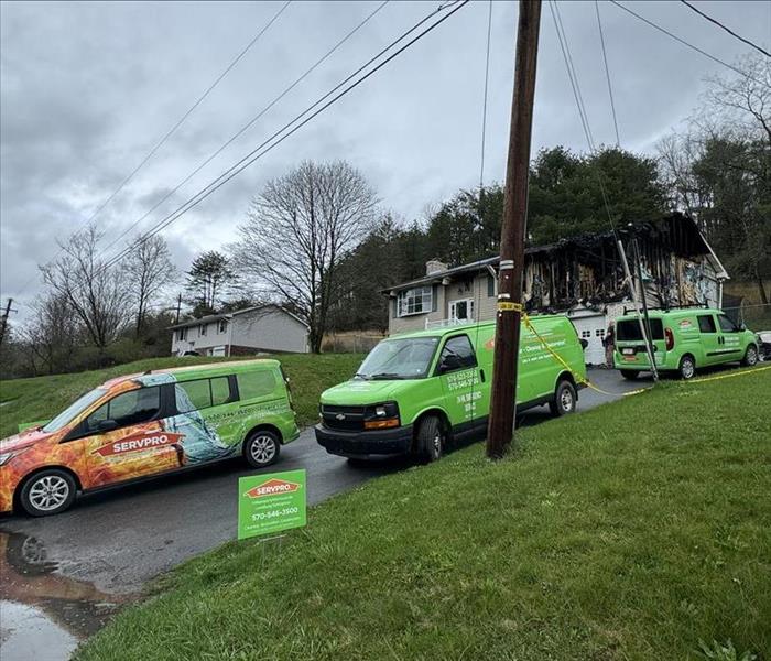 green vehicles on driveway in front of a house that had a fire